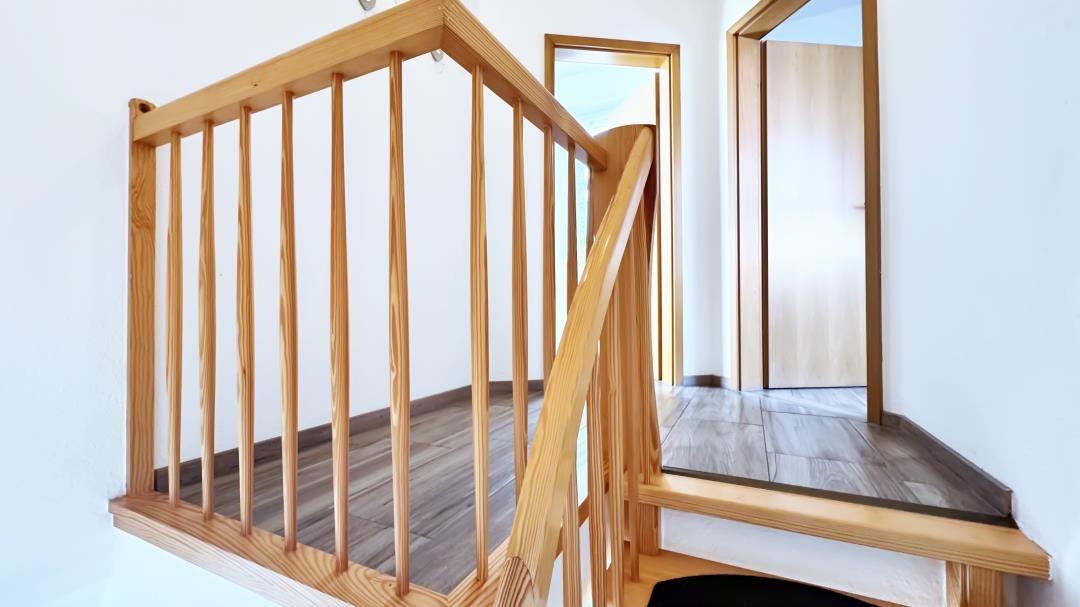 Holzgeländer und Treppenhaus mit Holzfußboden und weißen Wänden.