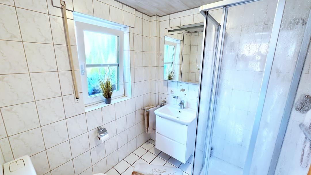 Badezimmer mit Dusche, Waschbecken und Fenster