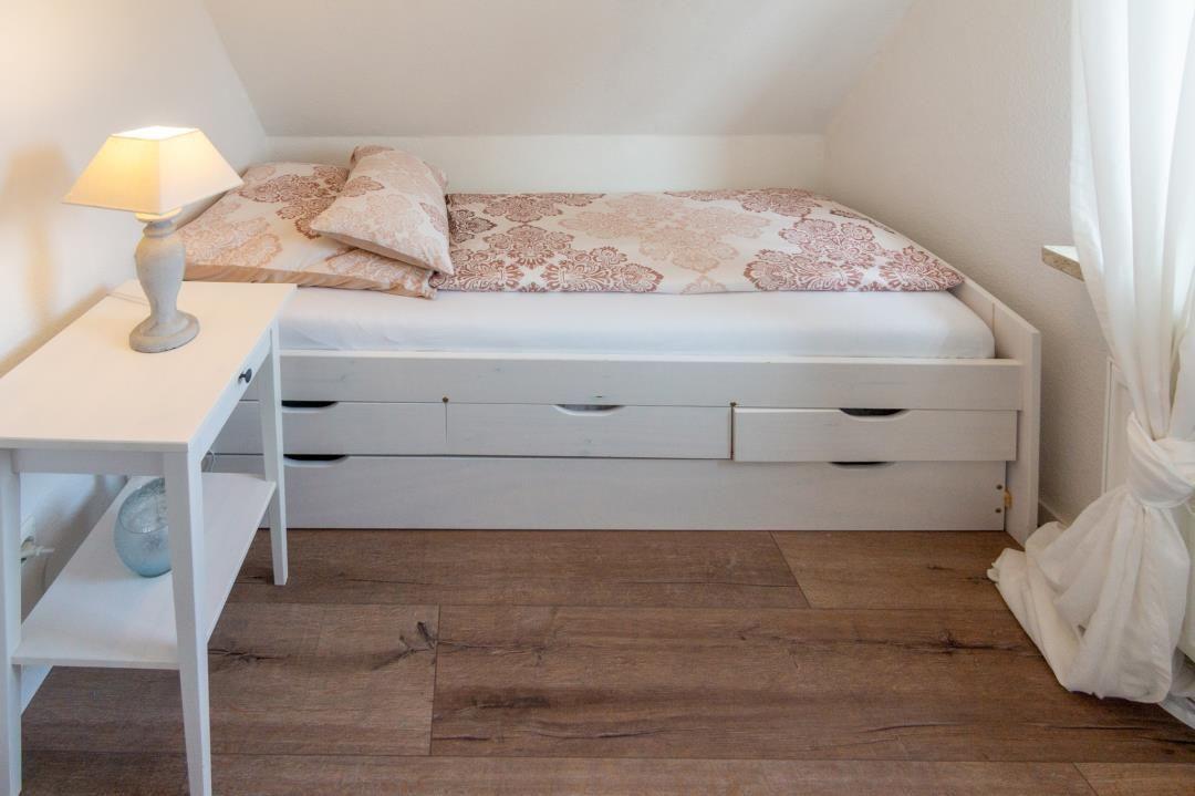 Schlafzimmer mit Doppelbett, Schubladen und Nachttisch unter Dachschräge
