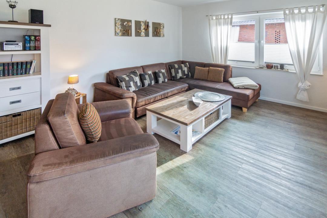 Wohnzimmer mit braunem Sofa, Holztisch und Bücherregal.