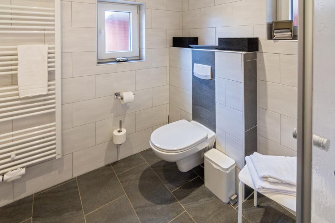 Badezimmer mit Toilette, Heizung und Fenster