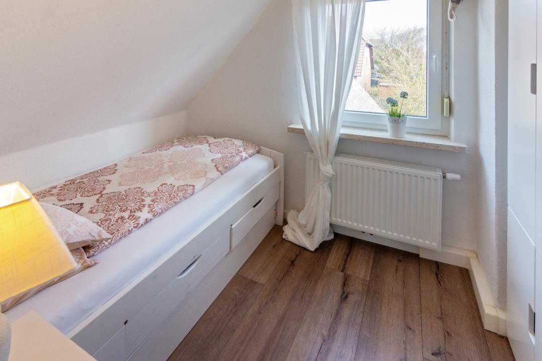 Schlafzimmer mit Dachschrägen, Bett, Fenster und Heizkörper.