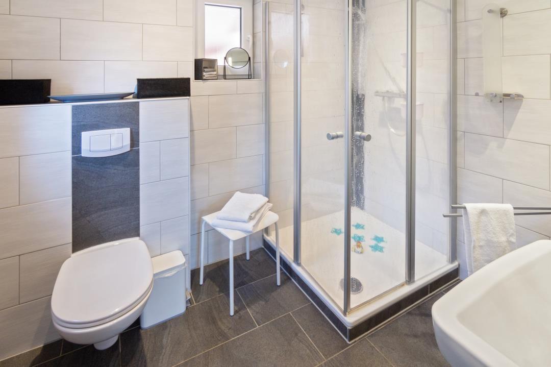 Bad mit Dusche, Toilette und Waschbecken. Duschwanne mit blauen Sternen.