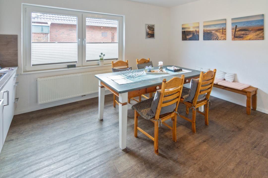Esszimmer mit Holztisch, Stühlen und Fenster. Wandbildern und Bank.