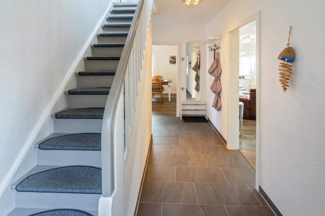 Hausgang mit Treppe und Blick in Wohn- und Essbereich.