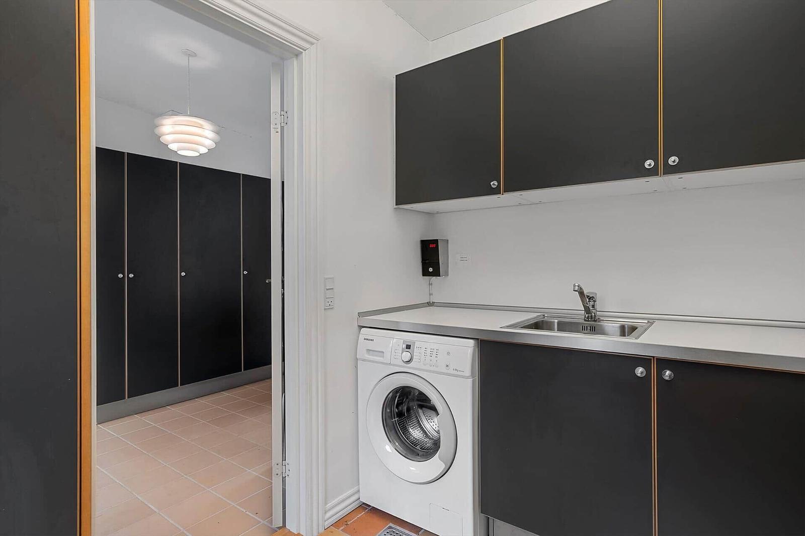 Washing machine and sink in a kitchen with black cabinets.