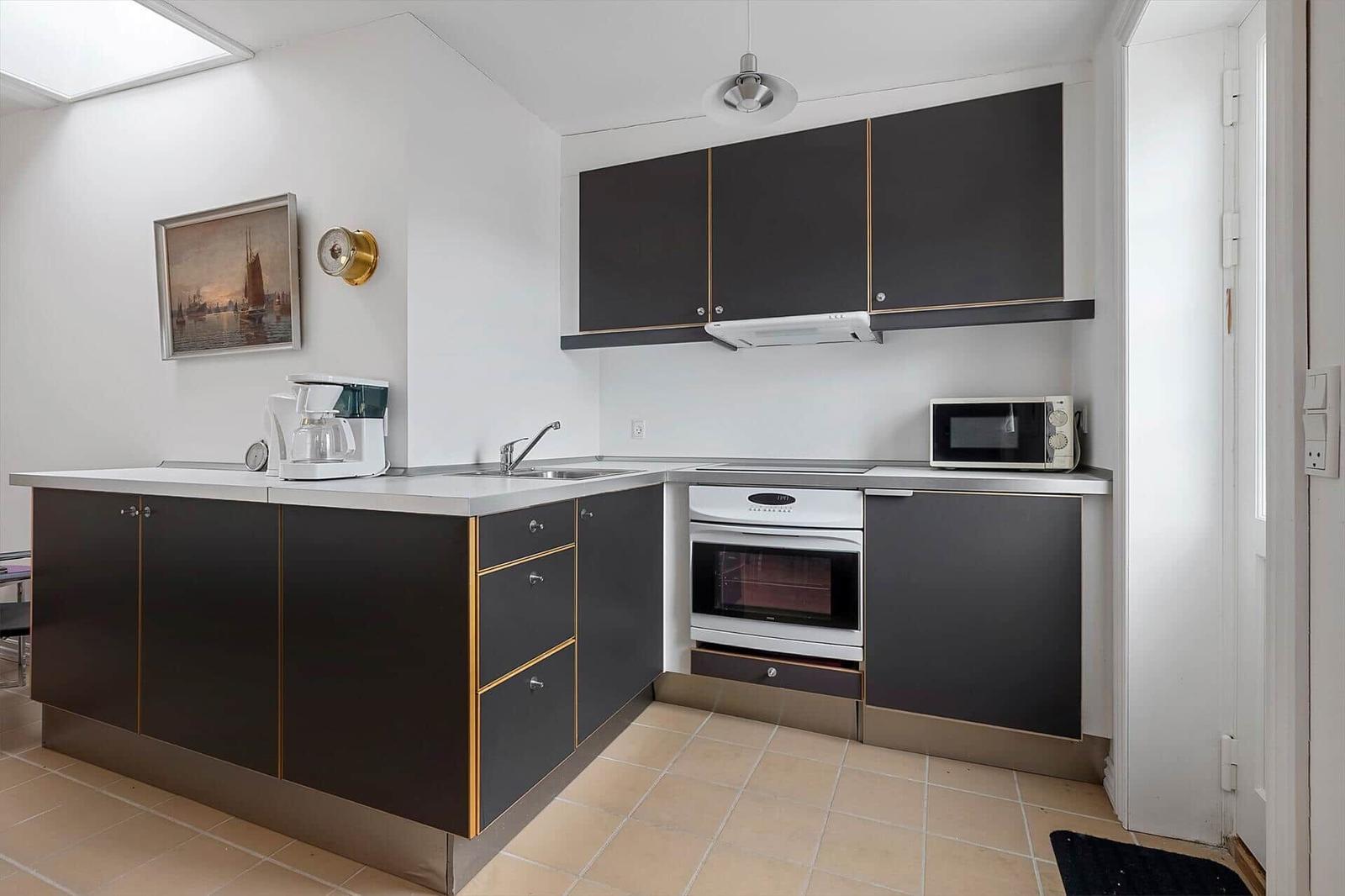 Kitchen with dark cabinets, stainless steel countertop, and built-in oven.