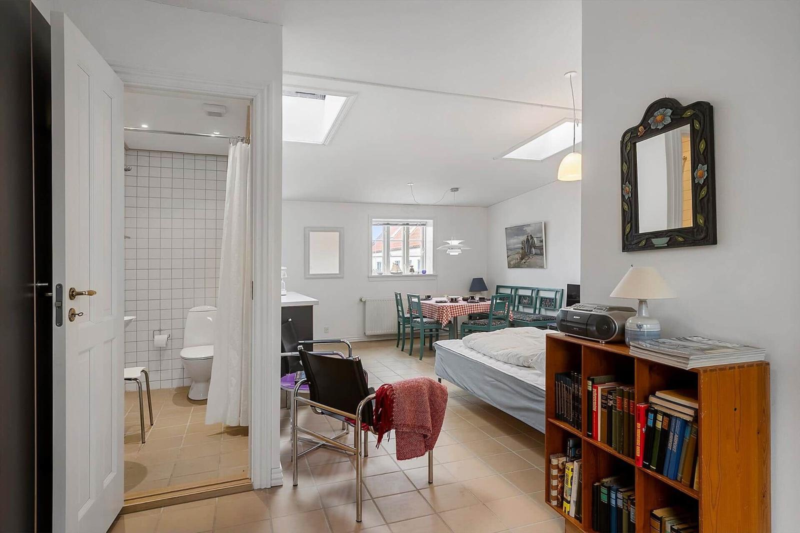 Bedroom with bed, bookcase, and view into bathroom.