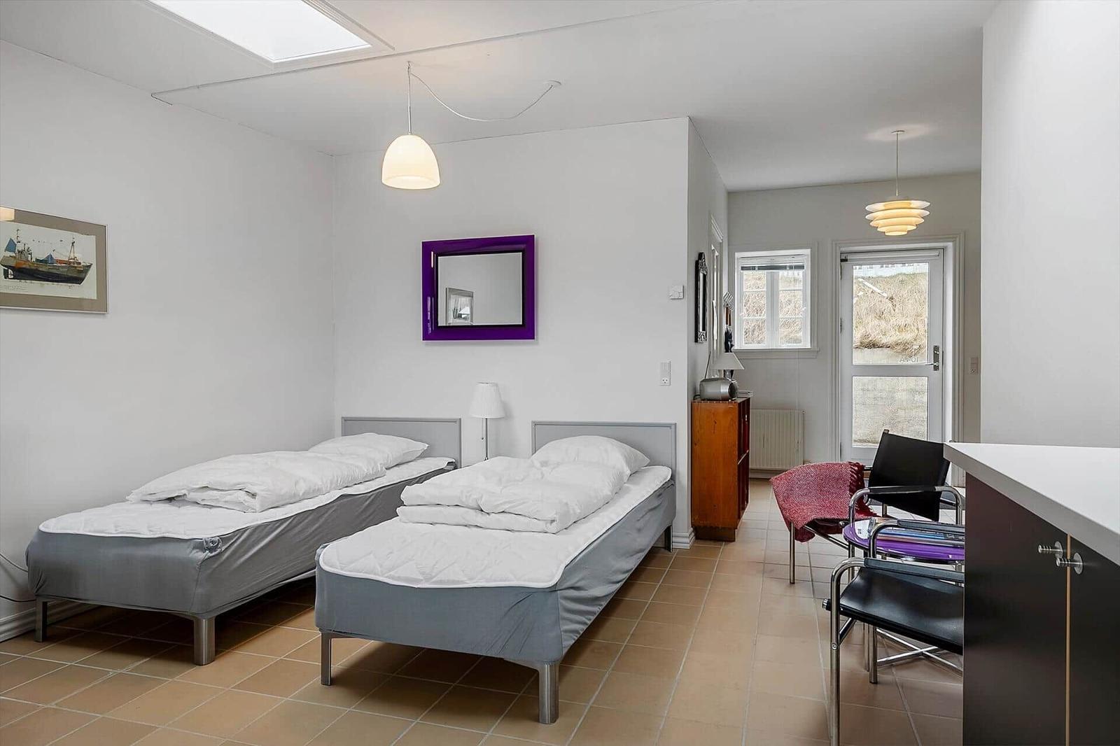 Two single beds, a mirror, and a window with view outside.