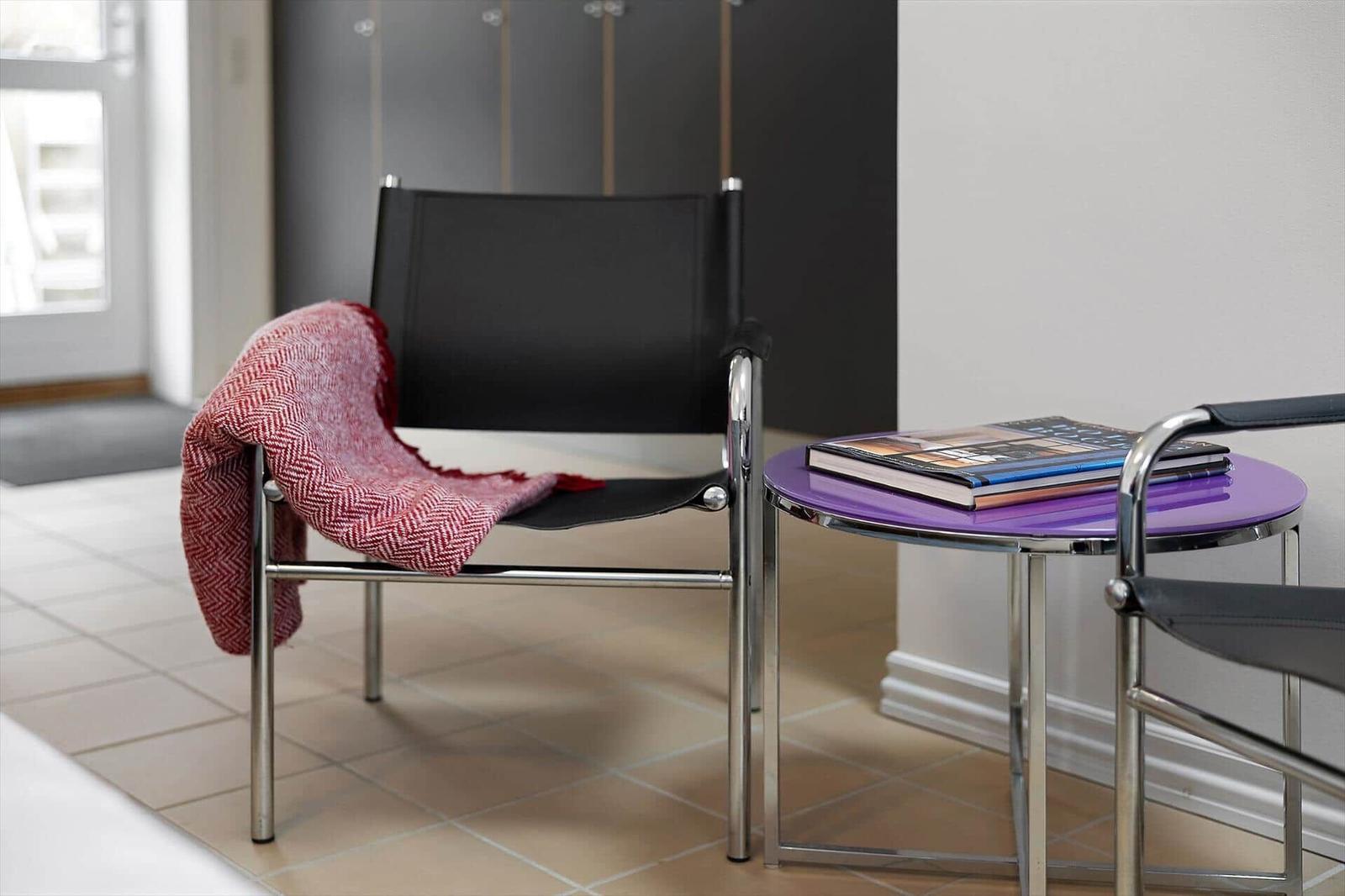 Black chairs with red blanket and purple table with books.
