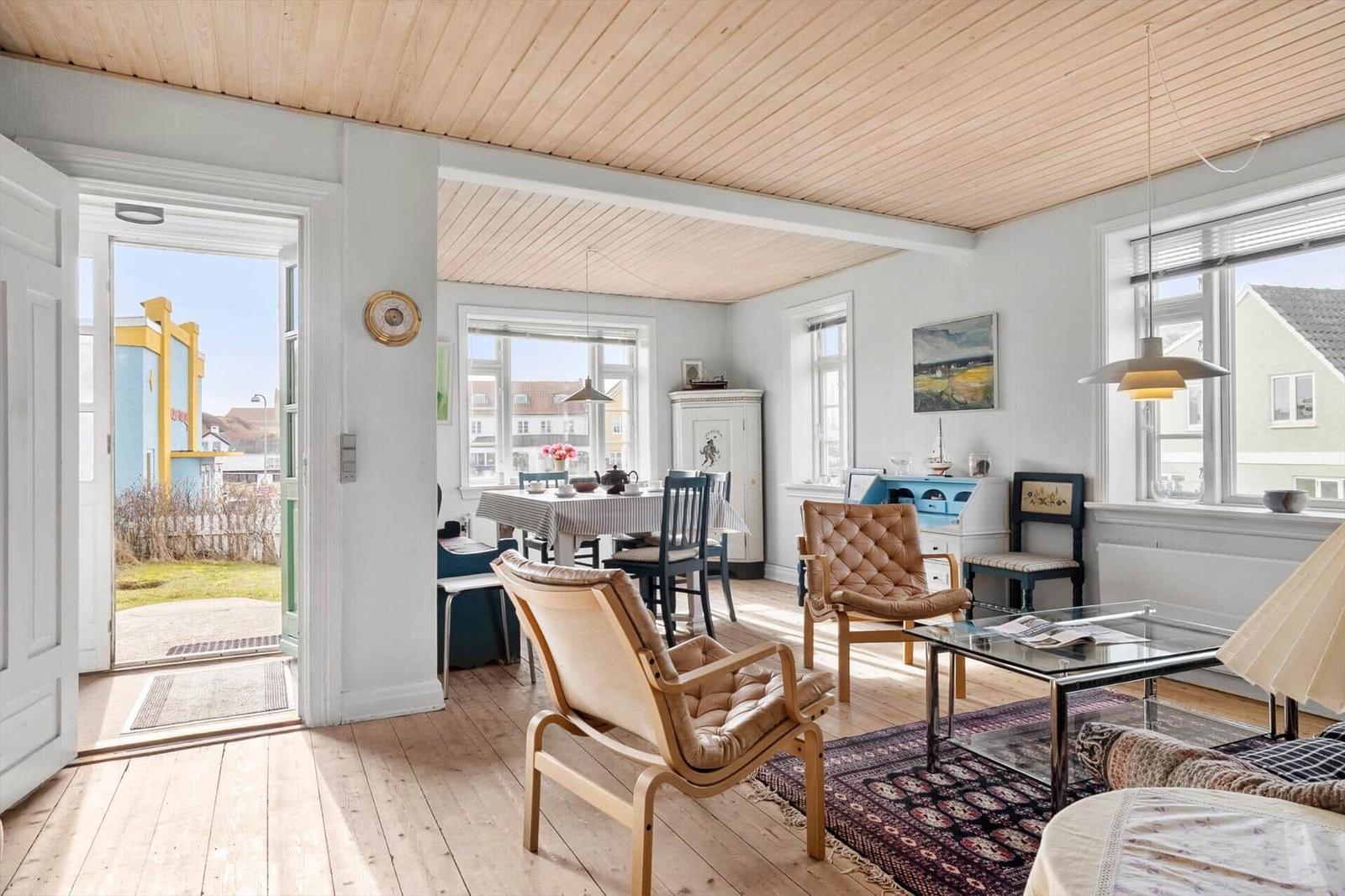 Living and dining area with wooden floor, windows, and chairs.