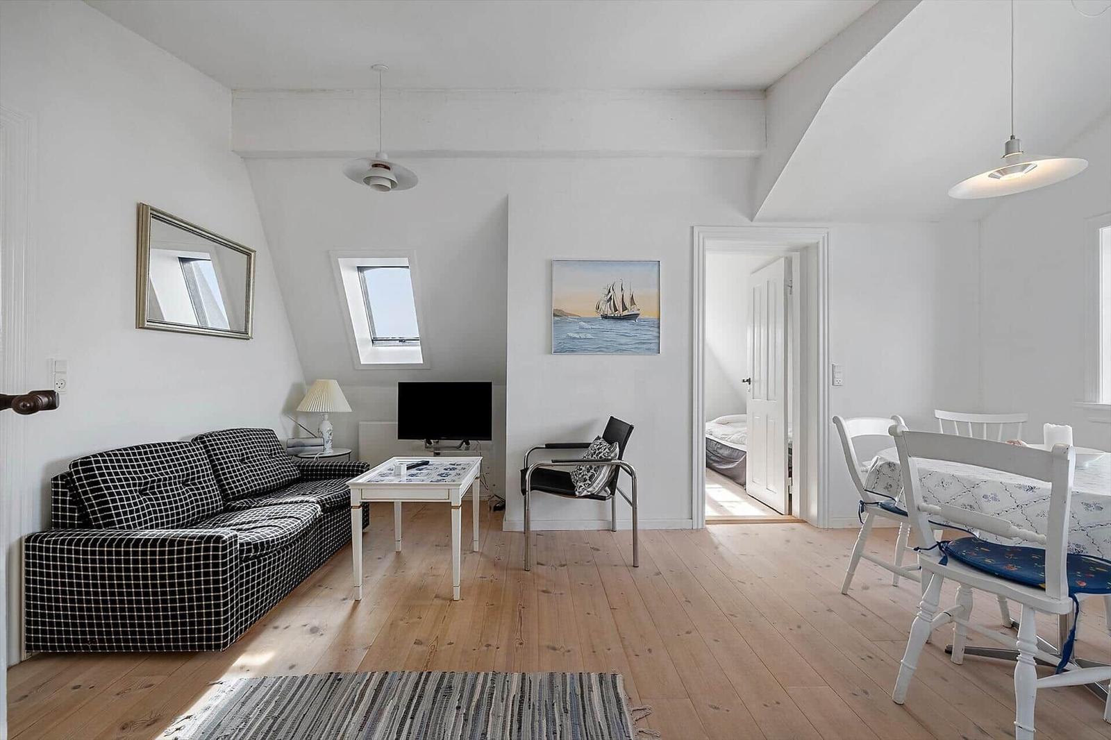 Living and dining area with sofa, table, chairs, and view into bedroom.