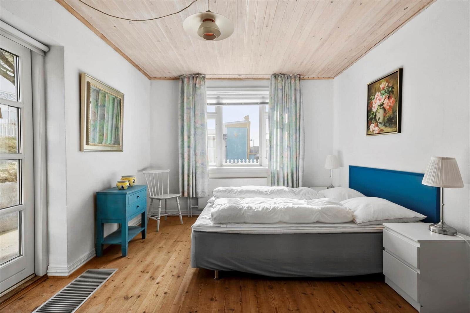 Bedroom with bed, nightstands, and window. Wooden ceiling and floor.