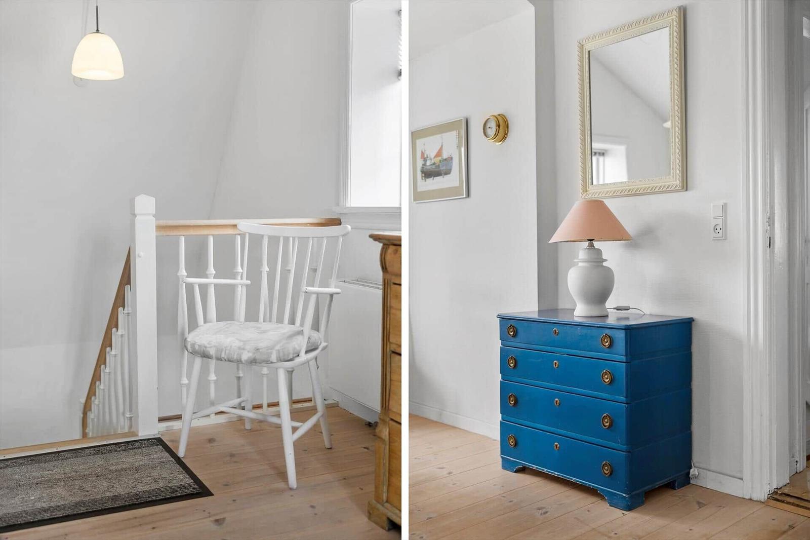 House with white walls, wooden floor, and blue dresser with lamp.