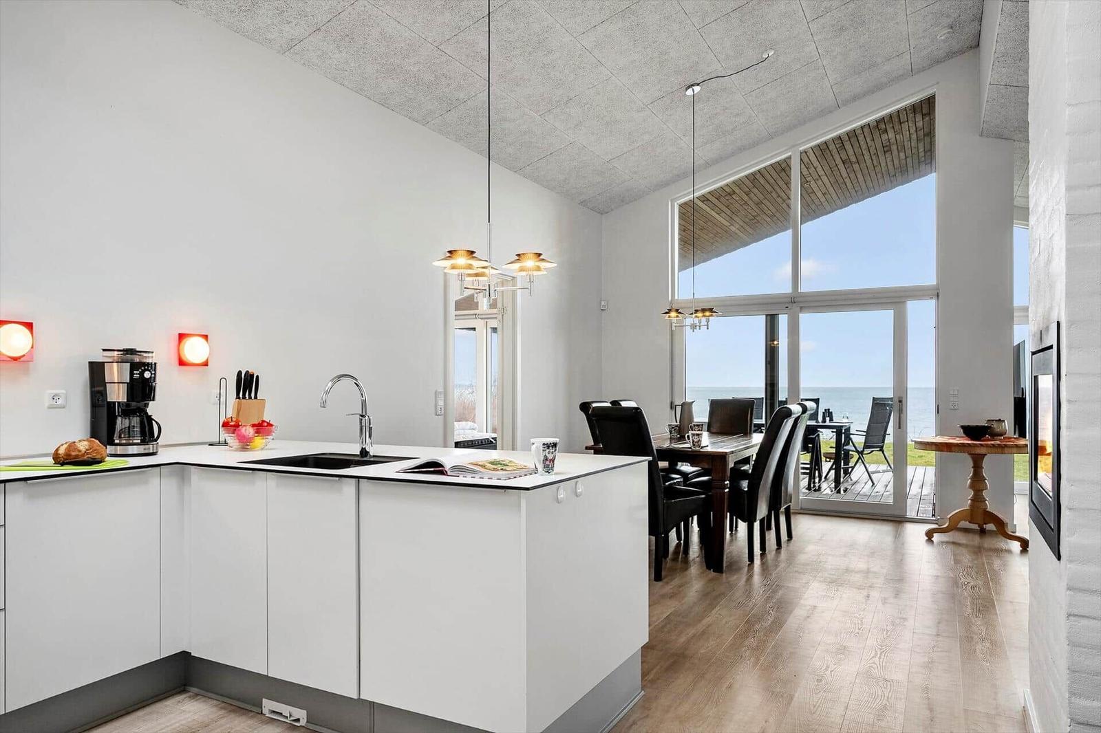 Kitchen with dining area and sea view through large windows.
