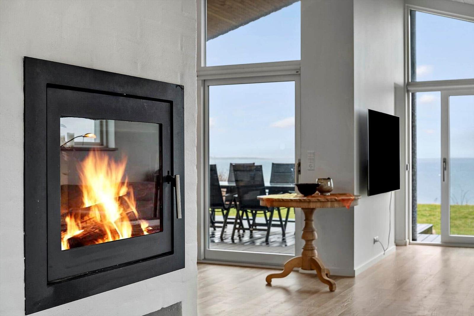 Living room with fireplace, TV, and view of terrace and sea.