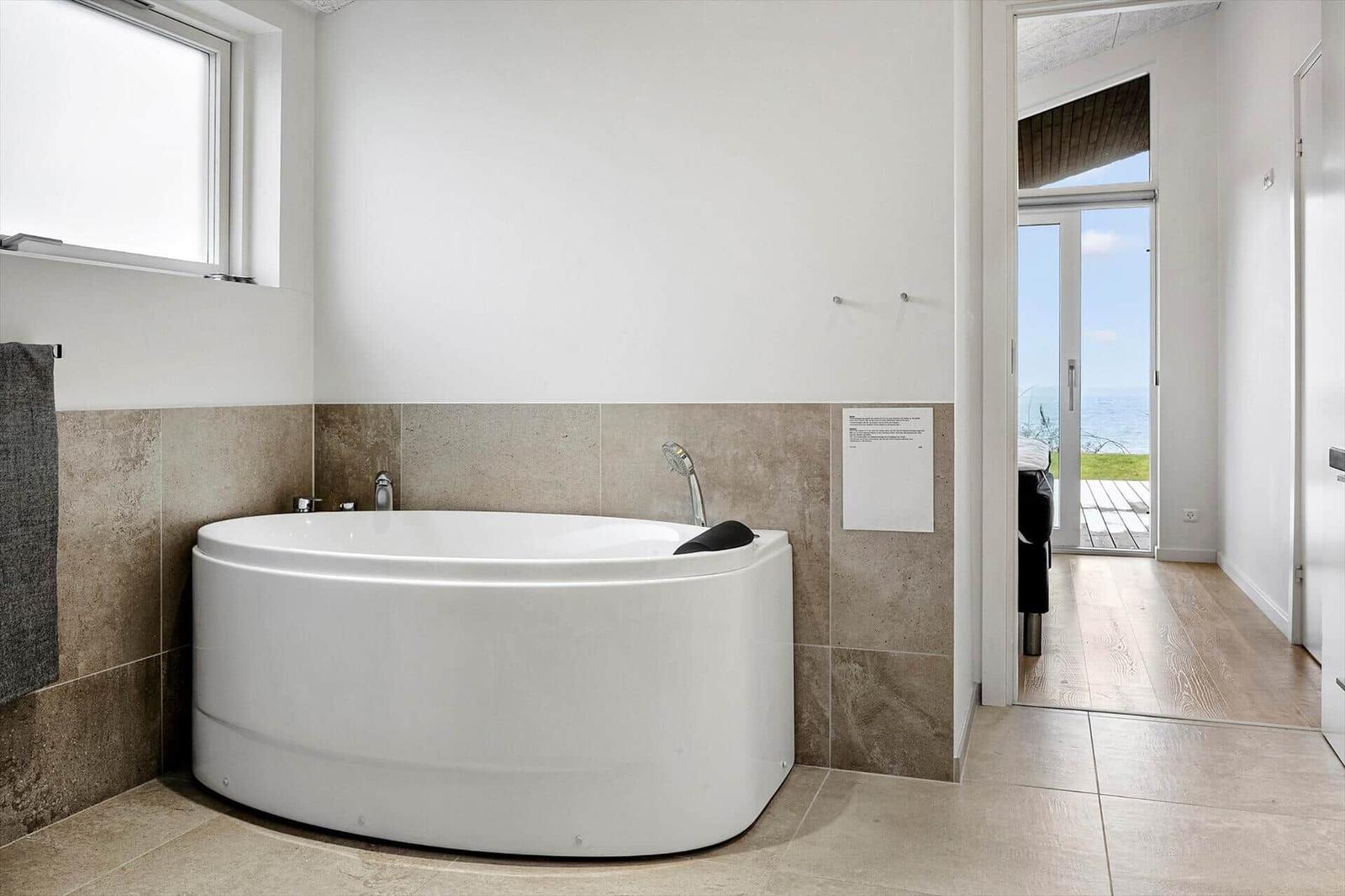 Bath with whirlpool tub, window, and view of the beach.