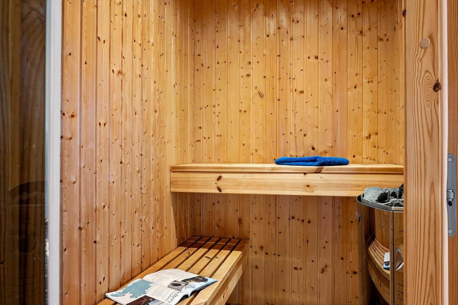 Wooden sauna with bench and blue towel.