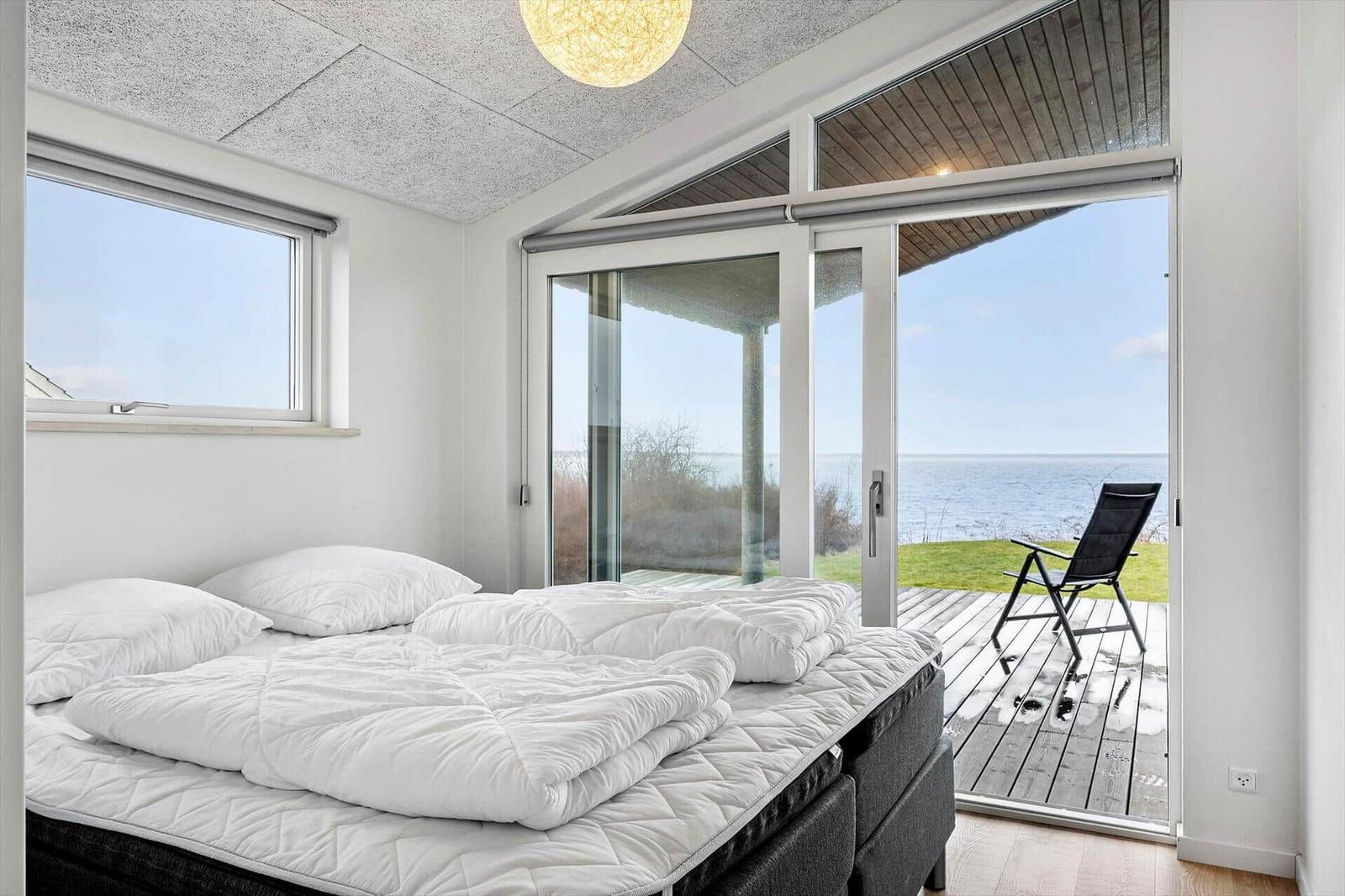 Bedroom with sea view and terrace with lounge chair.