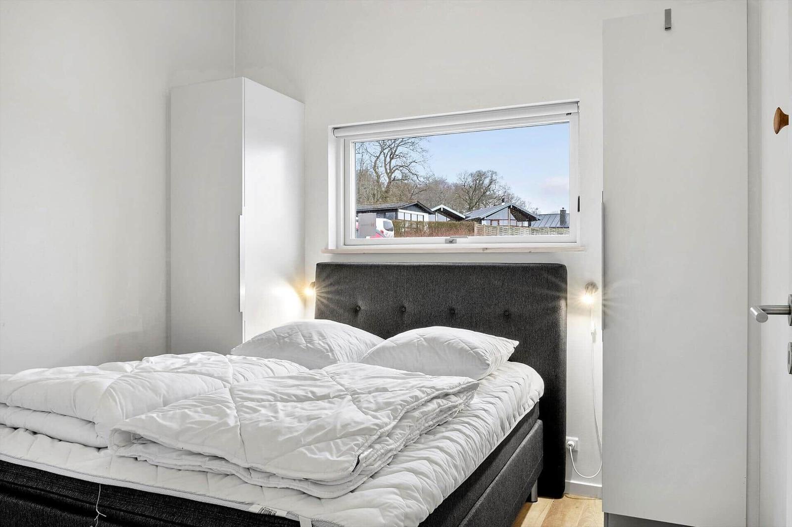 Bedroom with bed, window, and wardrobe.