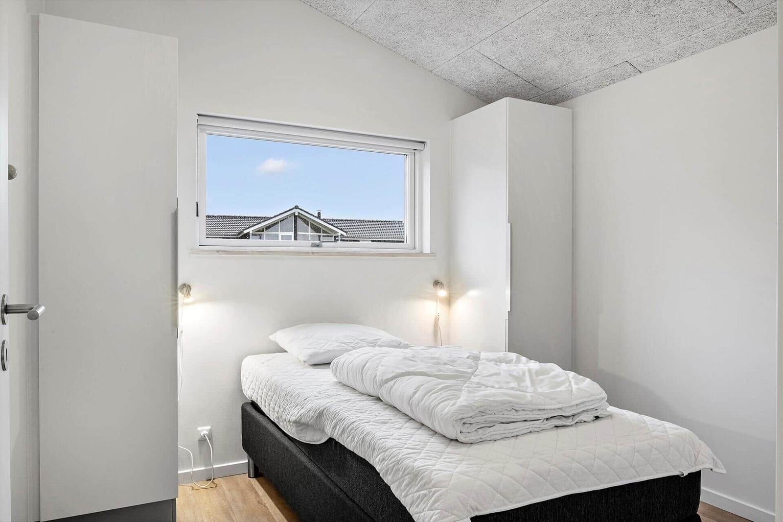 Bedroom with bed, window, and white cabinets.
