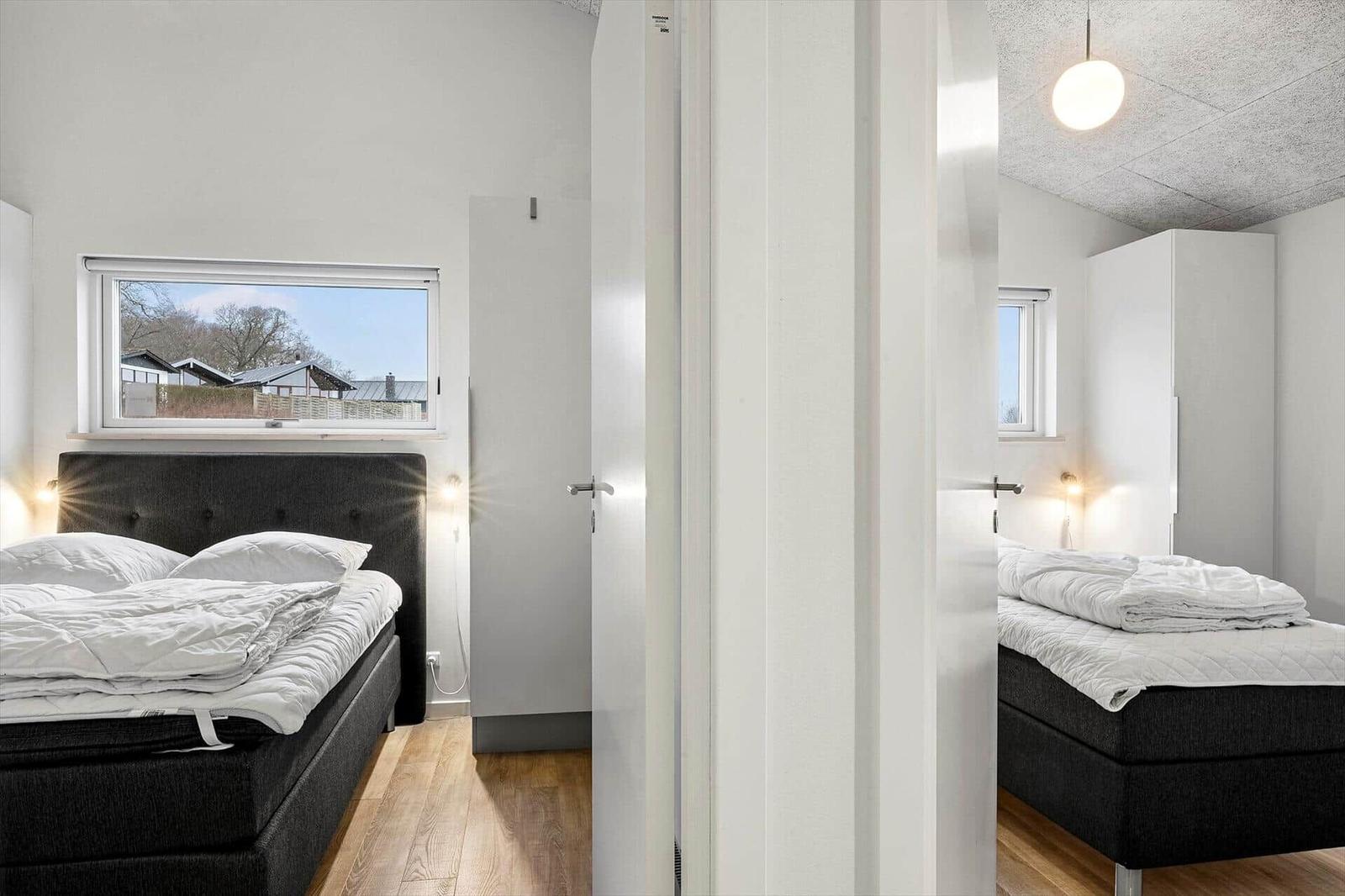 Two bedrooms with beds, windows, and white wardrobes. Wooden floor and ceiling light.