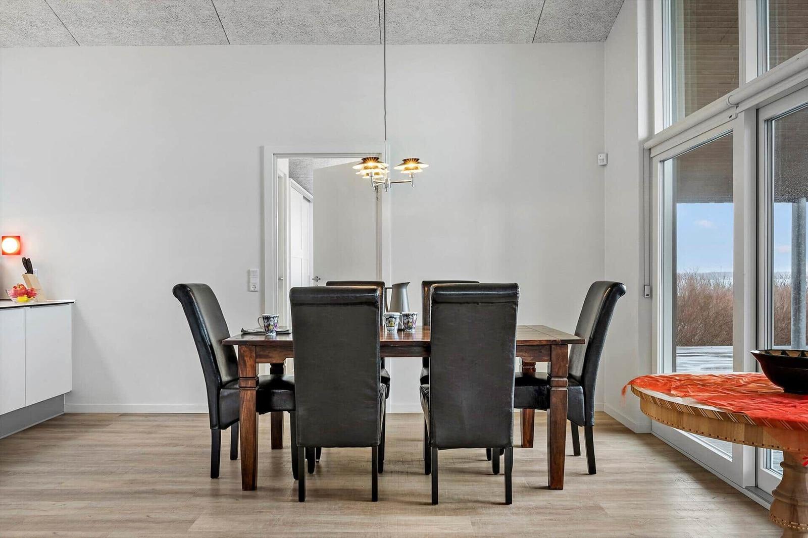 Dining room with wooden table, black chairs, and large window. Floor is wood.