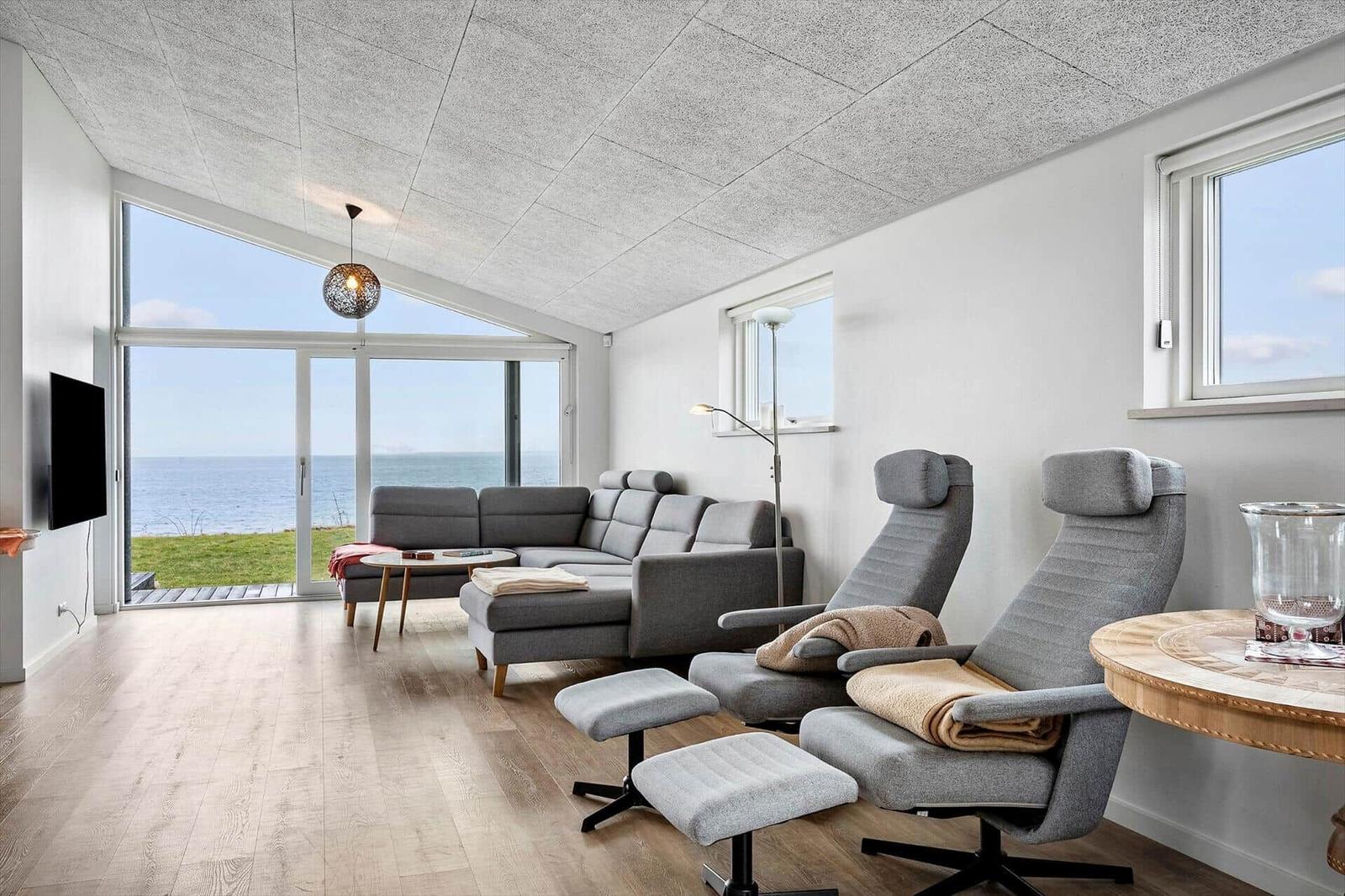 Living room with sea view, sofa, and two chairs.