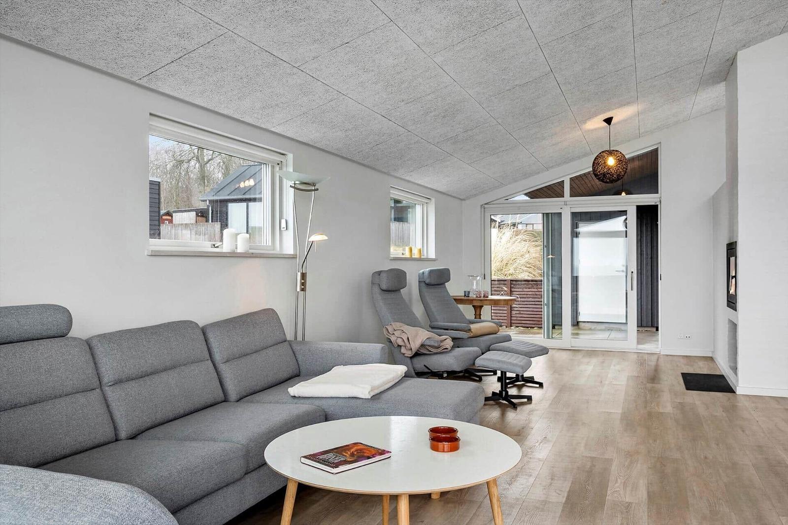 Living room with gray sofa, two chairs, and wooden floor. Entrance to terrace.