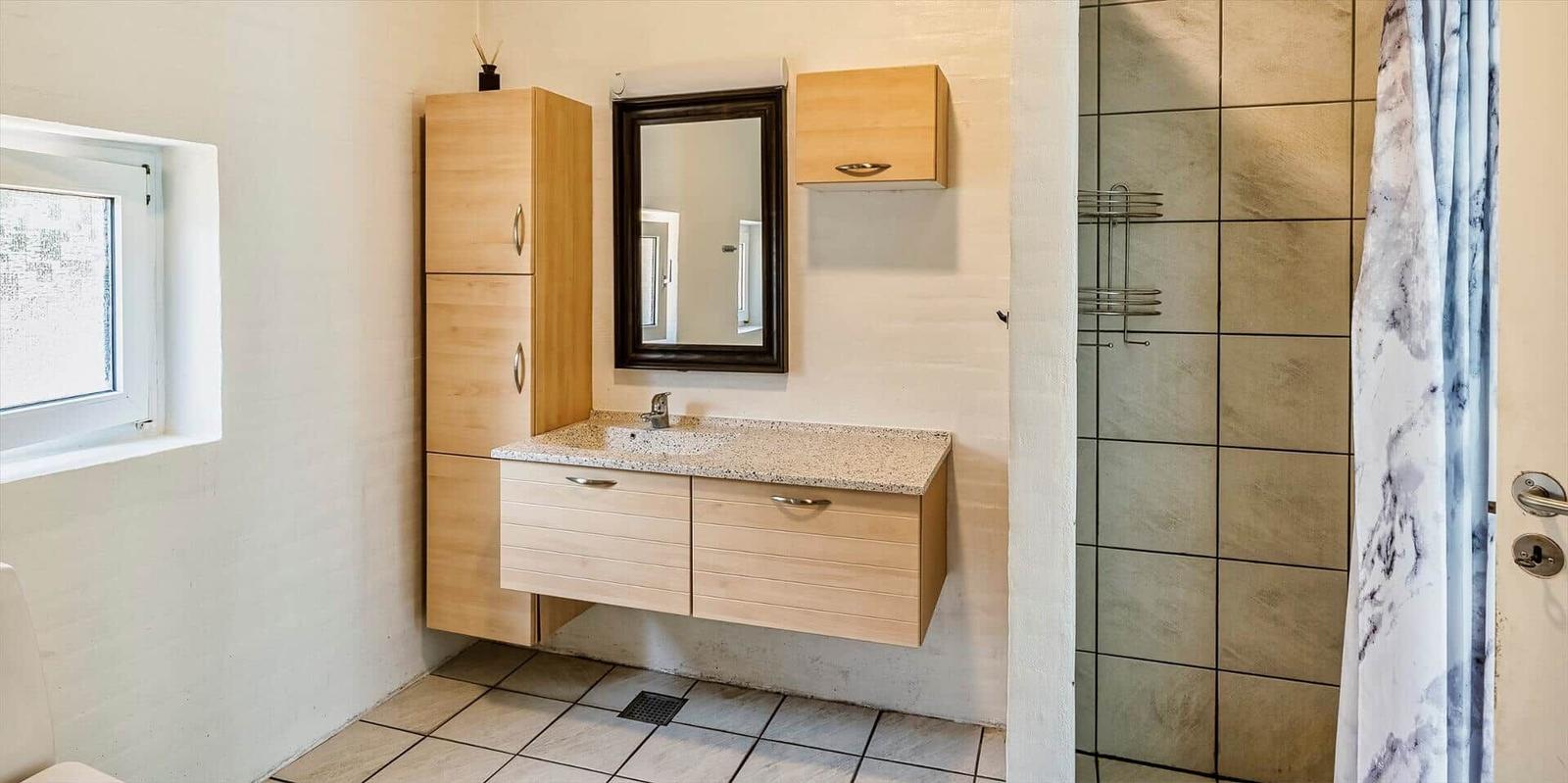 Bathroom with sink, mirror, shower, and window