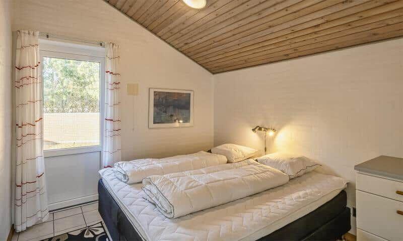 Bedroom with double bed, window, and wooden ceiling.