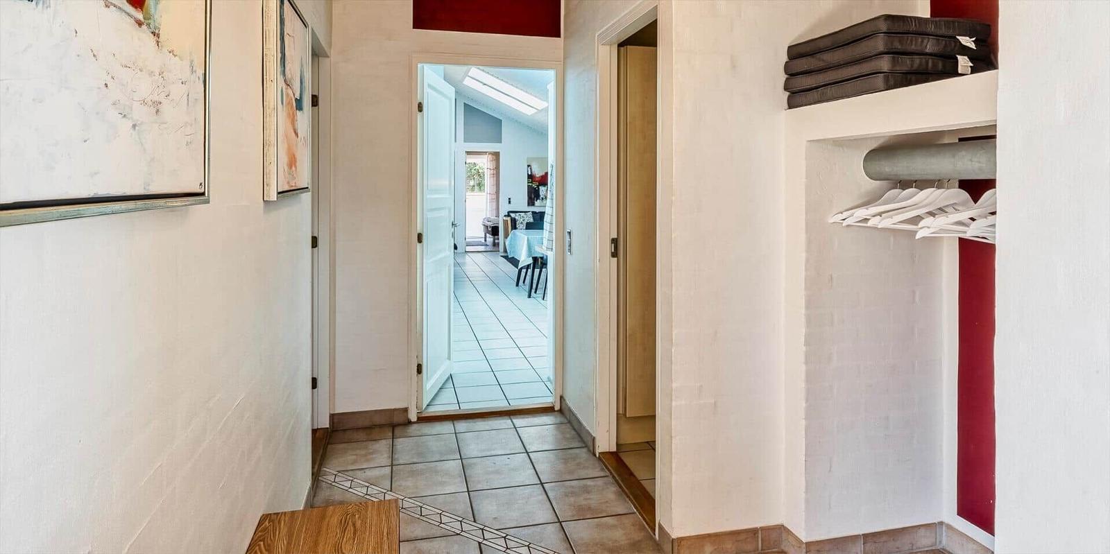 Hallway with closet, artwork, and view into dining area.