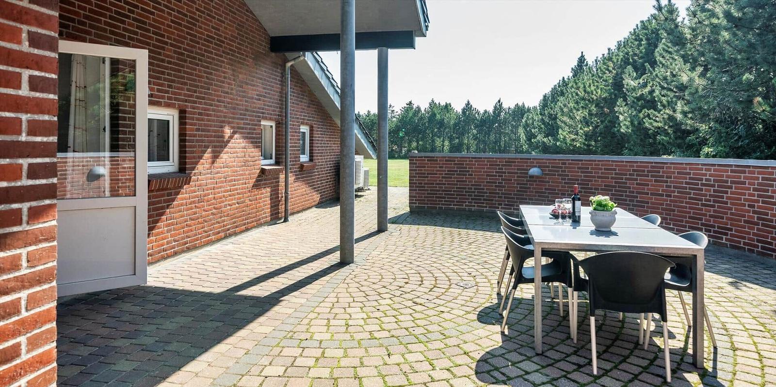 Terrace with table, chairs, and view of forest.
