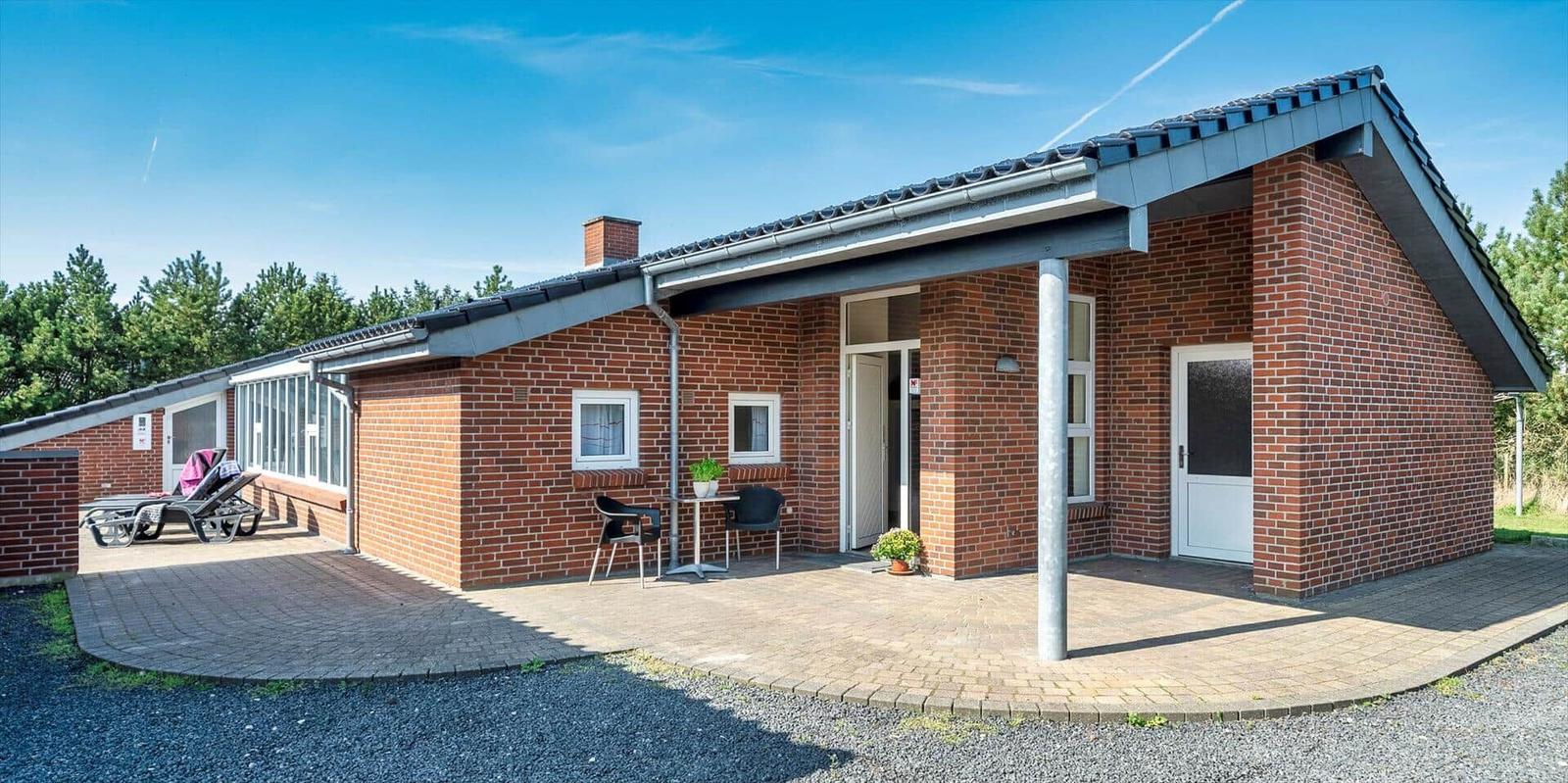 Single-story brick house with terrace and sun loungers.