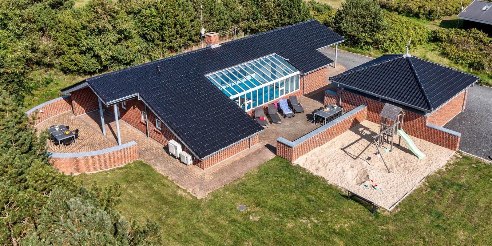 Modern holiday home with pool, playground, and grill area in green surroundings.