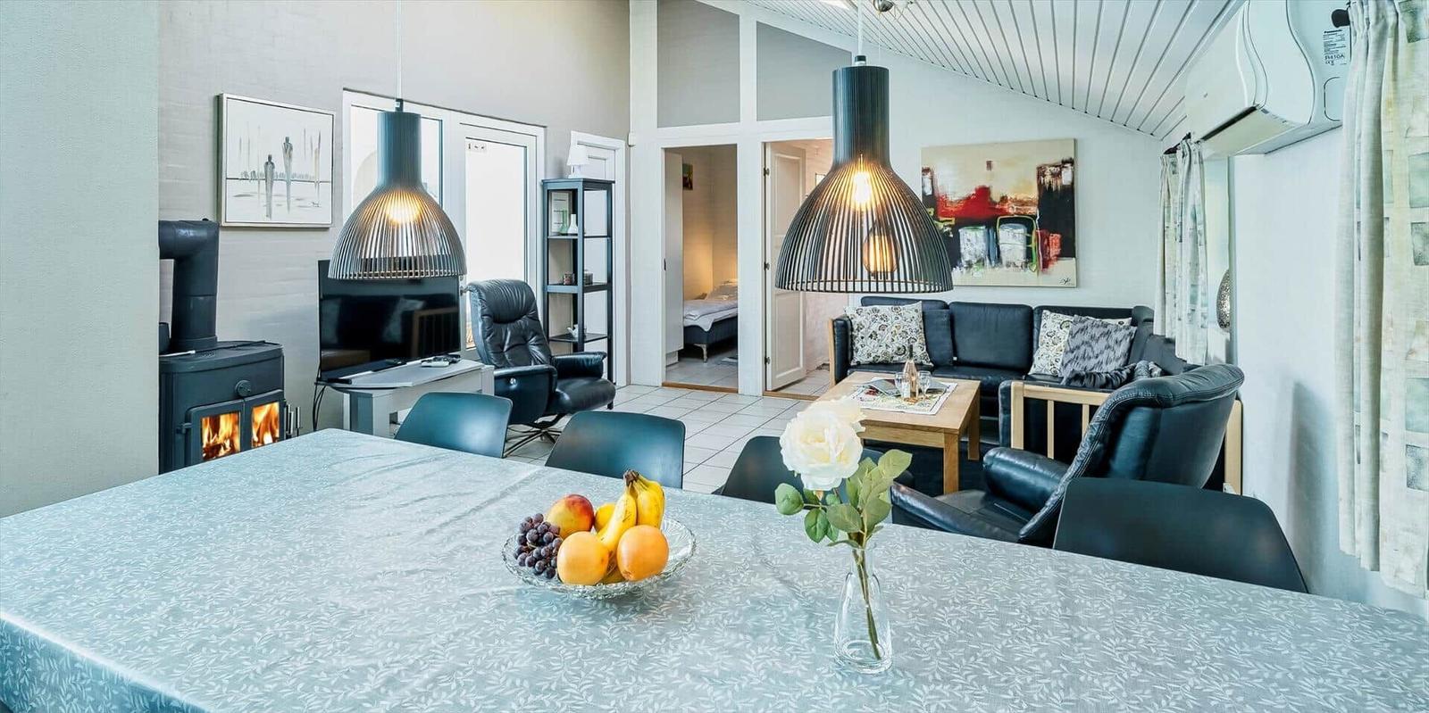 Dining room with dining table, sofa, and fireplace in background.