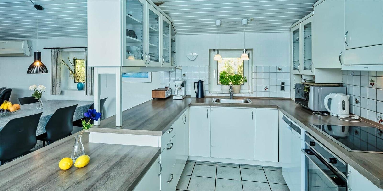 Kitchen with white cabinets, wooden countertops, and window with plant.