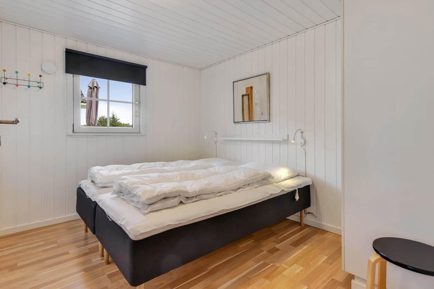 Bedroom with bed, window, and wooden floor.