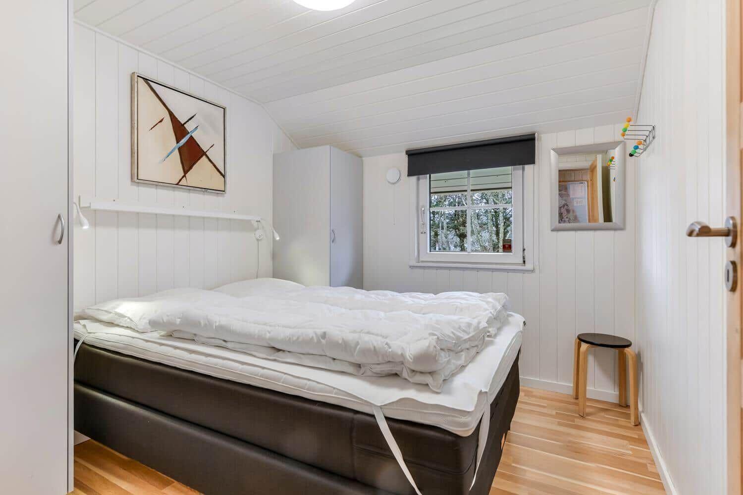 Bedroom with bed, wardrobe, and window with view of trees.
