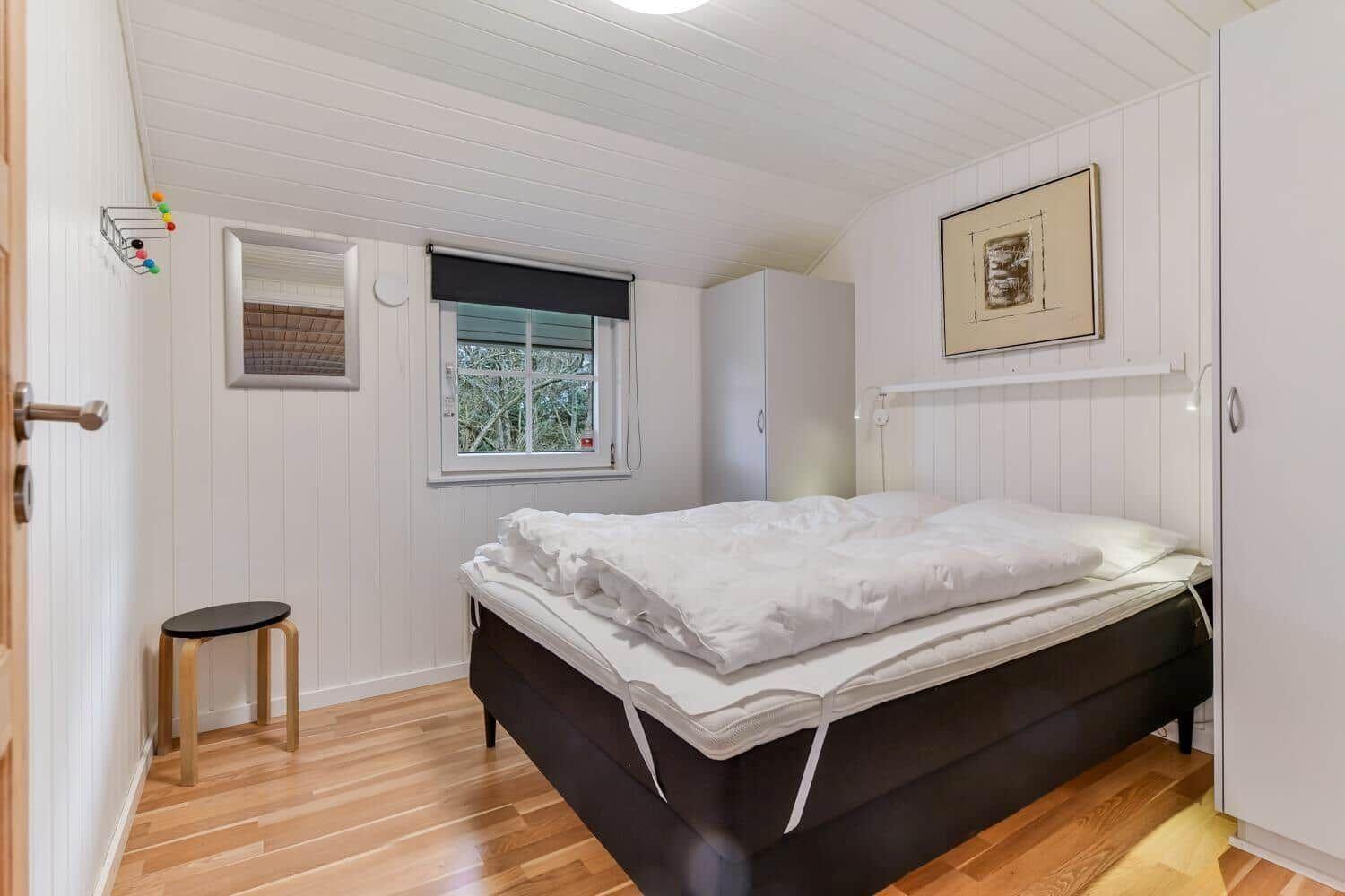 Bedroom with bed, wardrobes, and window with view of trees.