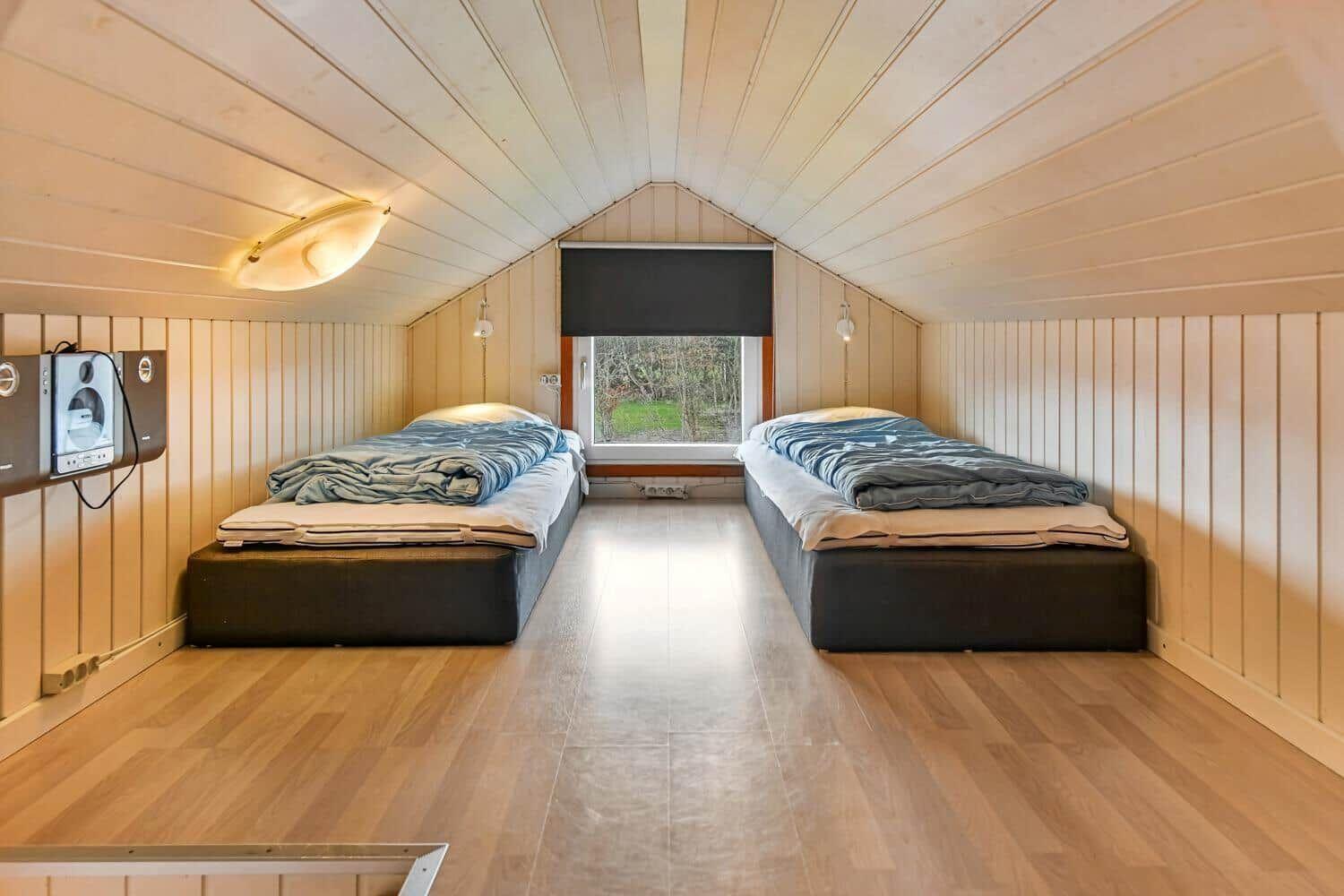 Two beds in a room with wooden walls and ceiling. Window with view outside.
