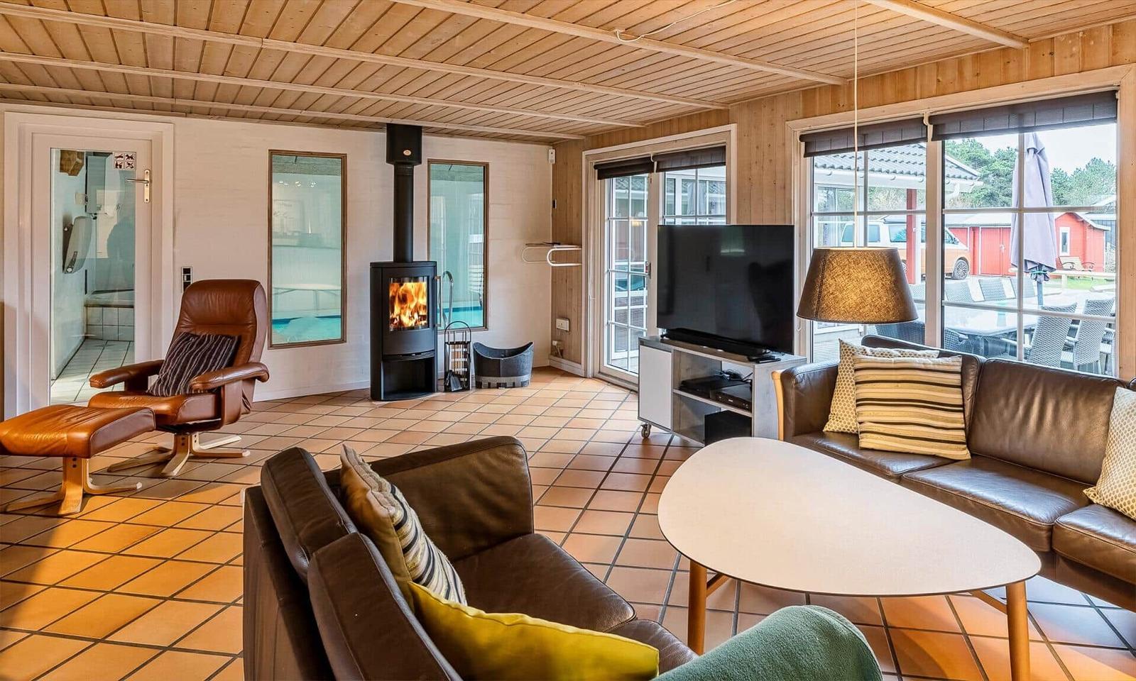 Living room with fireplace, sofa, and TV. Passage to shower and view of outdoor area.