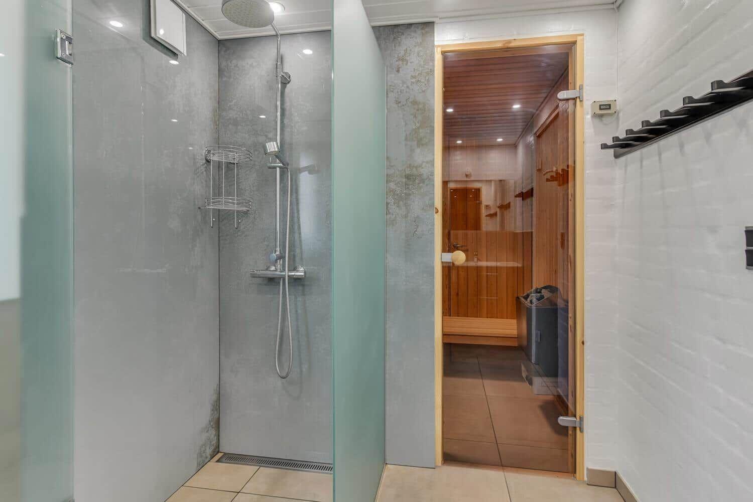 Shower with rain showerhead and sauna in background