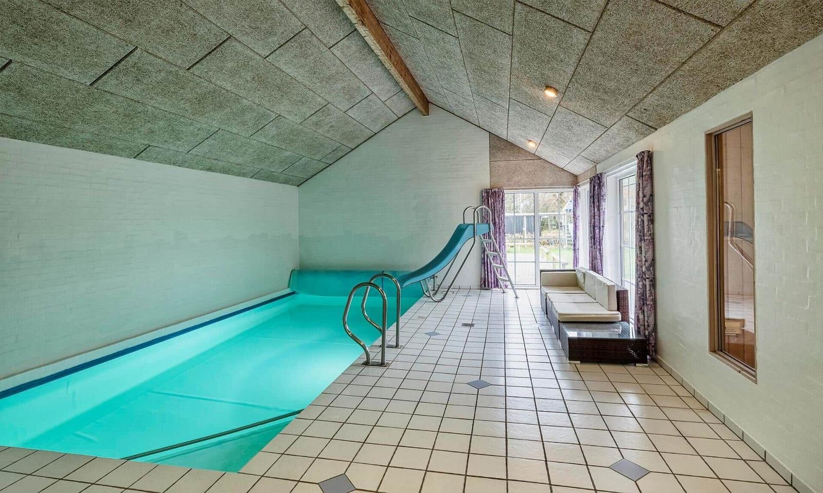 Indirectly lit indoor pool with slide and seating area.