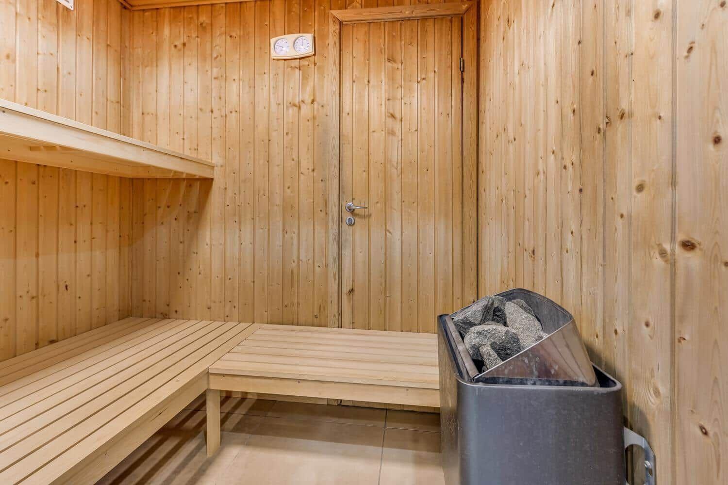 Sauna with wooden walls, benches, and stone bin