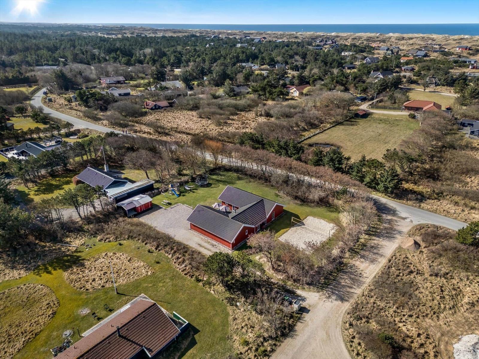 Red houses with garden and beach in the background.
