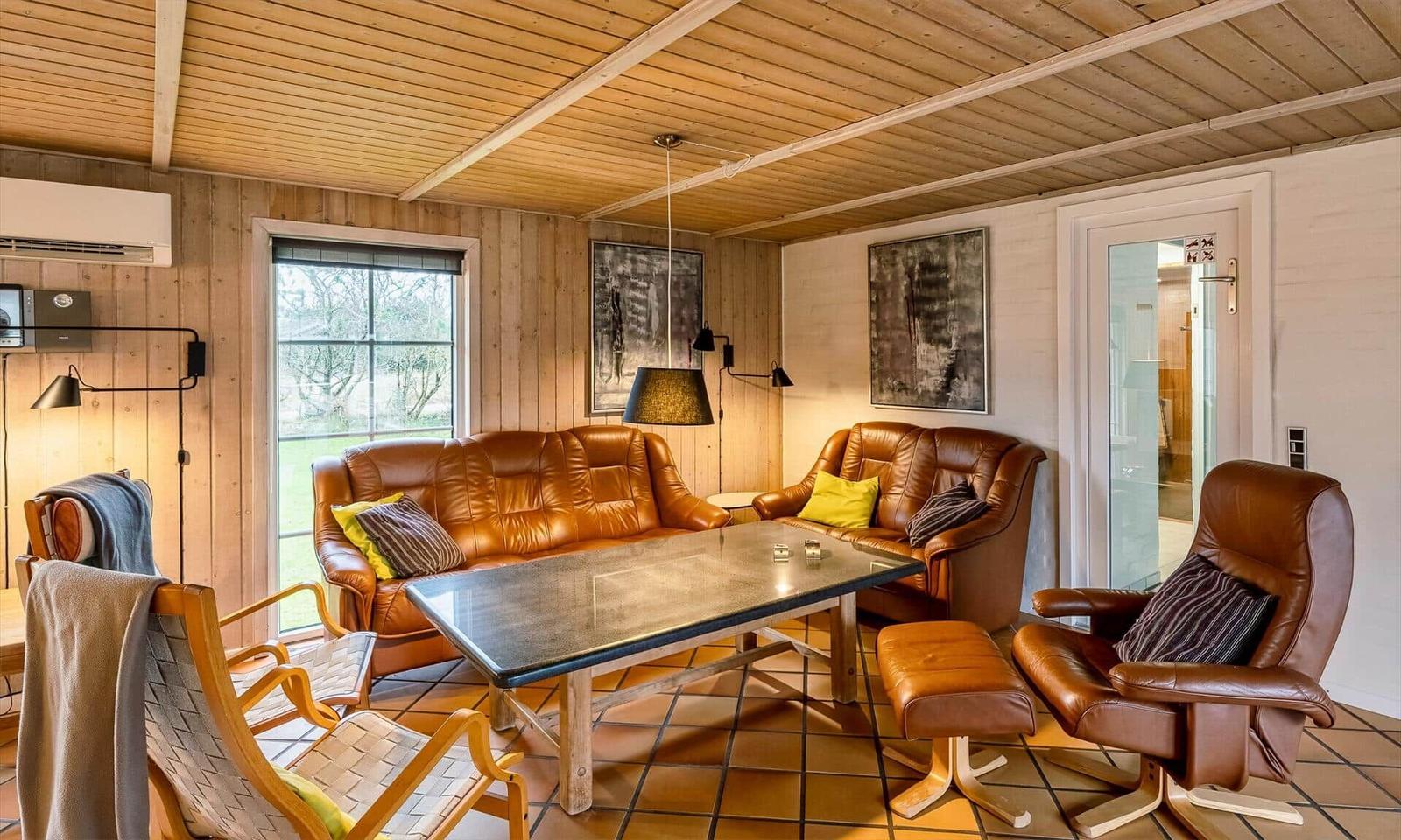 Living room with brown leather furniture, wood walls, and glass door.