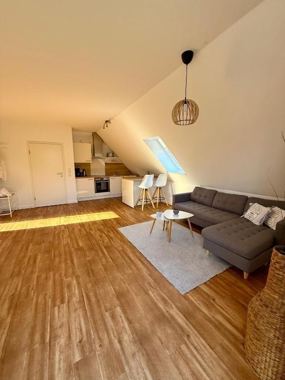 Wohnbereich mit Sofa, Couchtisch und Küchenbereich unter Dachschrägen.