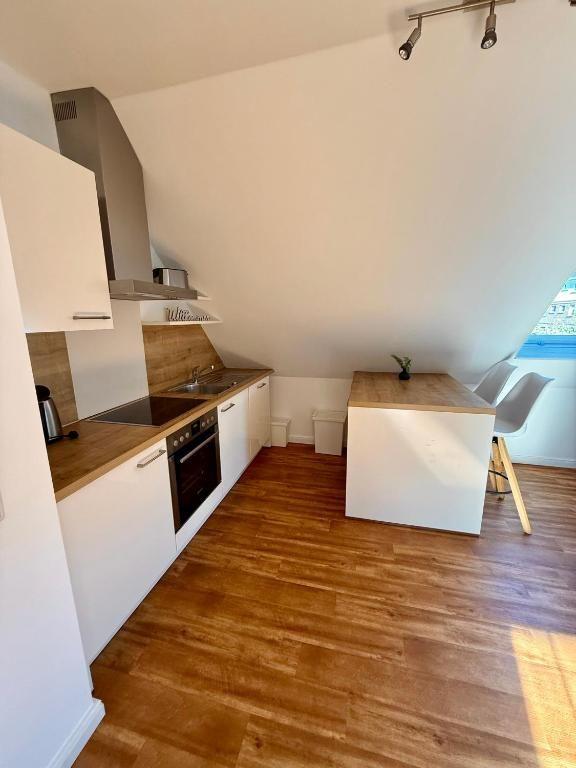 Küche mit Holzboden, Arbeitsplatte und Essbereich unter Dachschrägen.