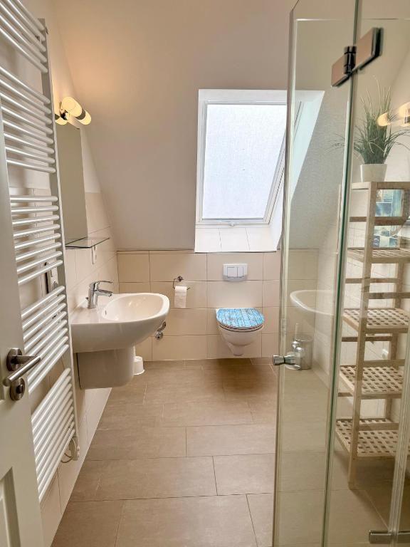 Badezimmer mit Dusche, Toilette und Waschbecken unter Dachfenster.